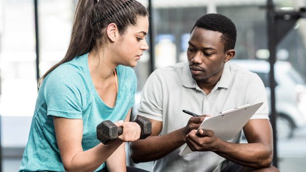 trainer-giving-advice-to-woman-at-crossfit-gym-P3JM27Z.jpg